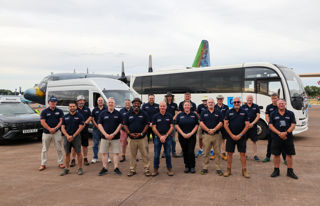 Volunteer team at RIAT25 in front of minibus and aircraft.