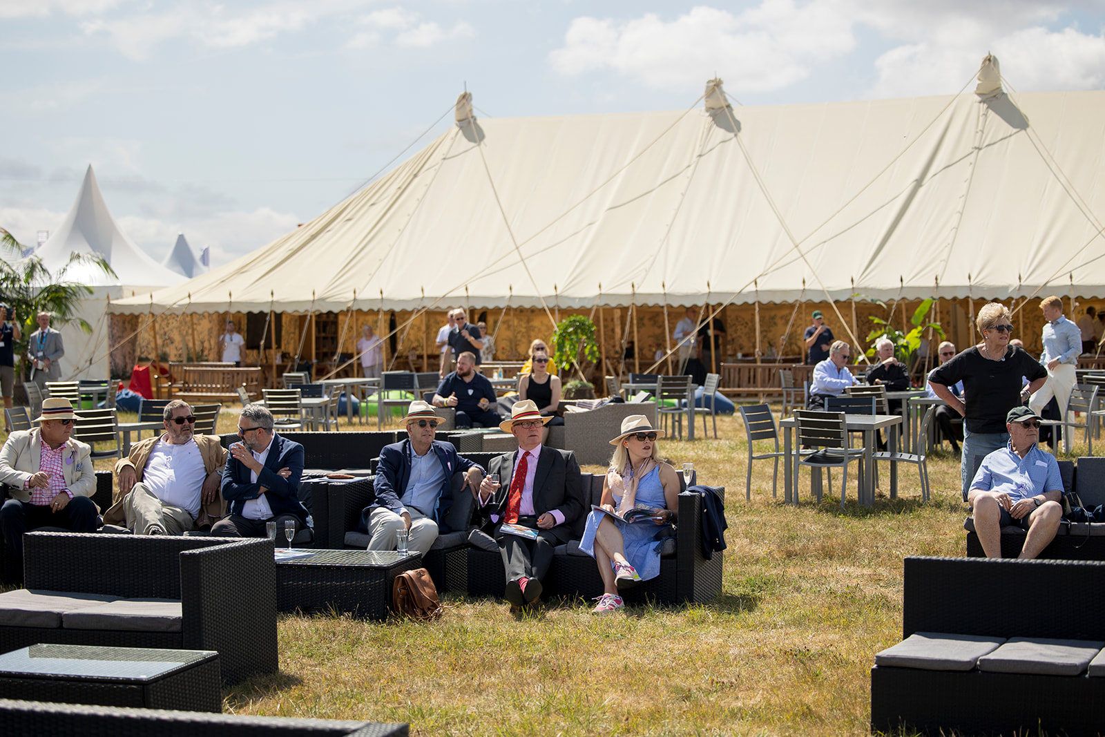 First Class Lounge guests on outdoor sofas at RIAT25 with marquee in the background.