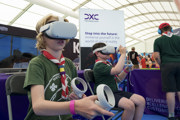 Scouts in the Techno Zone at RIAT24 wearing virtual reality headsets with controllers in front of the DXC sign.