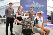 Child in the Techno Zone at RIAT24 wearing virtual reality headset and goggles, pointing.