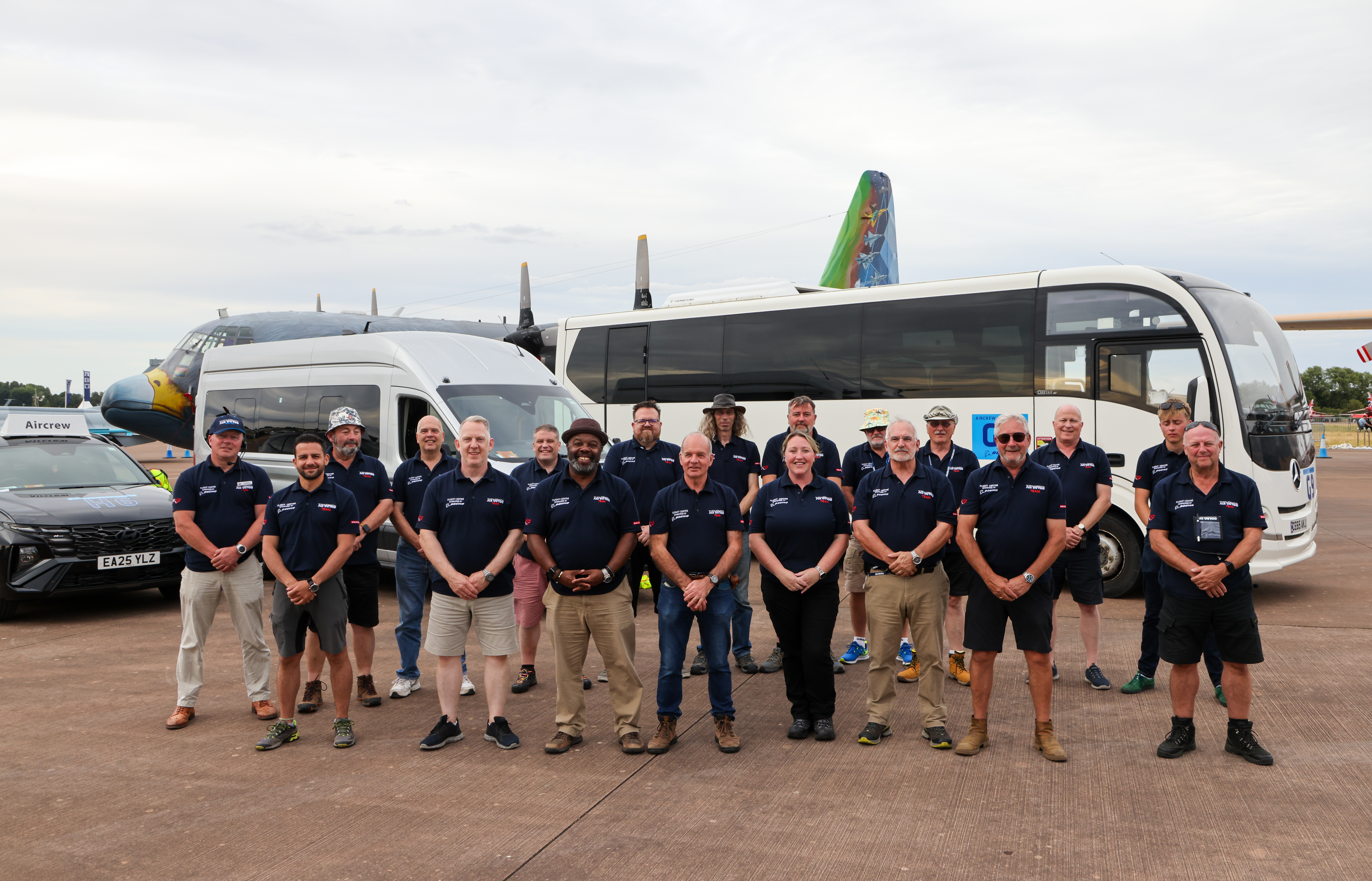 Volunteer team at RIAT25 in front of minibus and aircraft.