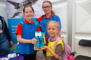 A girl holding a robot in front of two other girls on Friday Futures' day at RIAT25.